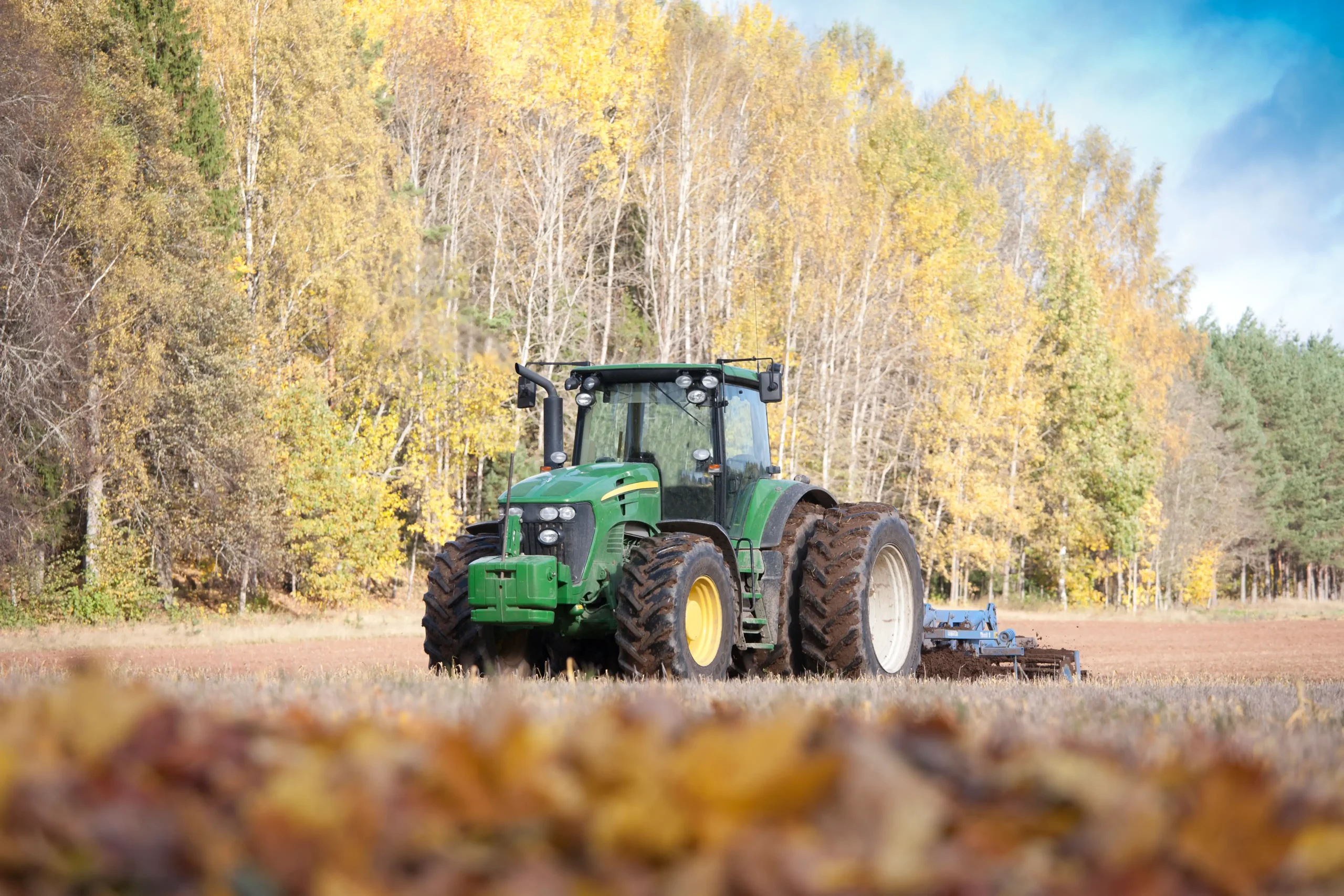 grön traktor som kör runt på en åker